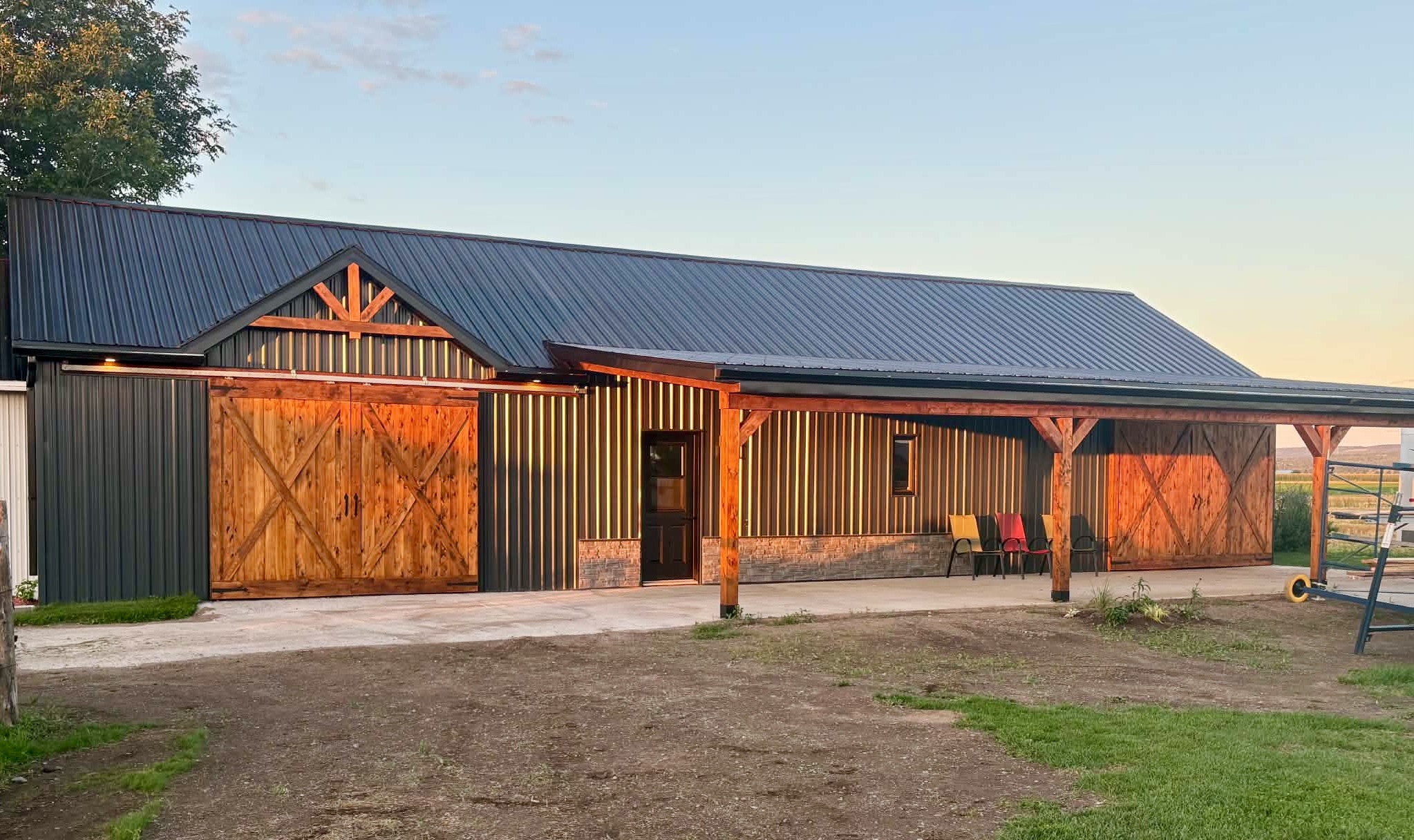 Garage avec toit de tôle de style grange avec de grandes portes de bois et une base de ciment coulée